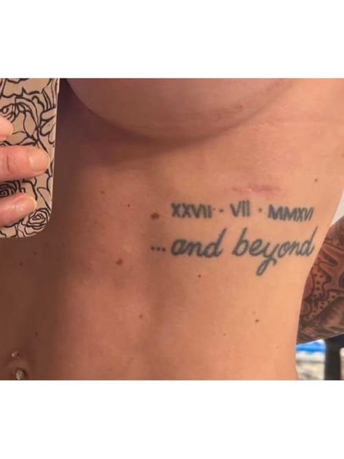 A minimalist black and grey tattoo featuring roman numerals and the phrase '...and beyond' on the rib — by Melanie Benoit, los angeles