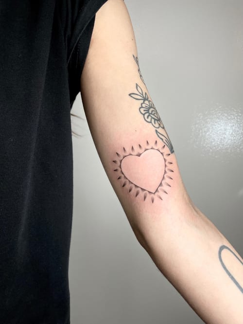 A minimalist blackwork heart tattoo with spikes on the inner arm — by Brian Kies, los angeles