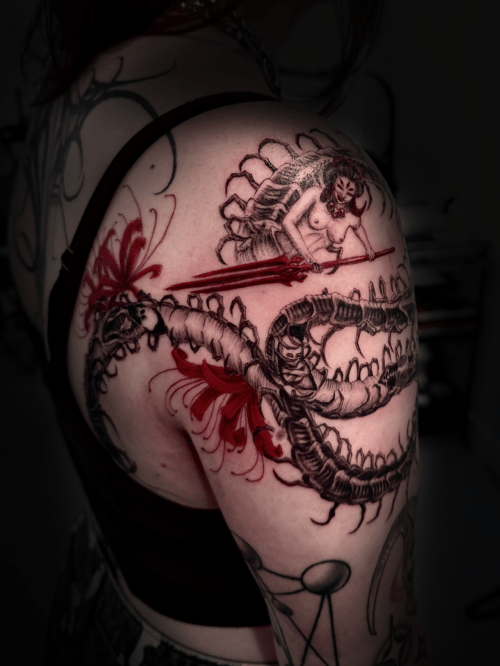 A mixed color tattoo on the shoulder featuring a woman wielding a sword against a dragon, with Japanese and blackwork influences — by zitronxus, los angeles