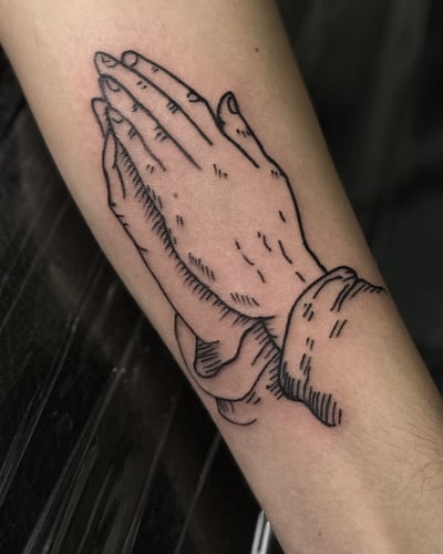 A minimalist blackwork tattoo of praying hands on the forearm — by Maddie Ramirez, los angeles