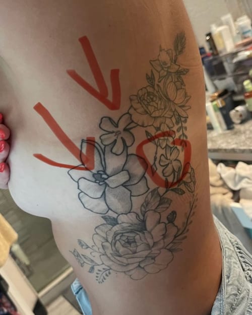A delicate black and grey floral bouquet tattoo on the rib, featuring various flowers in a detailed design — by Melanie Benoit, los angeles
