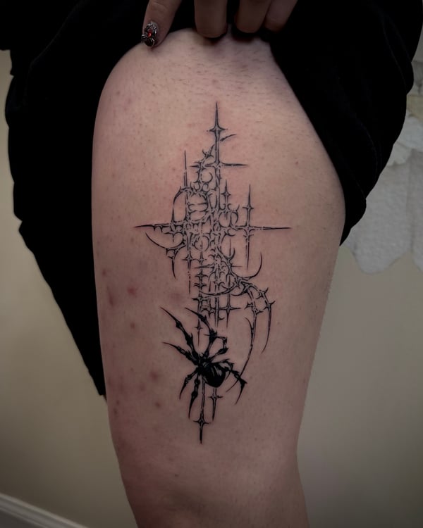 A black and grey abstract blackwork tattoo on the thigh featuring a stylized spider with intricate linework and sharp edges — by emily, rahway