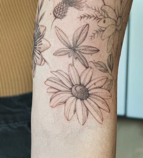 A delicate black and grey fine line floral tattoo on the forearm featuring various flowers — by Melanie Benoit, los angeles