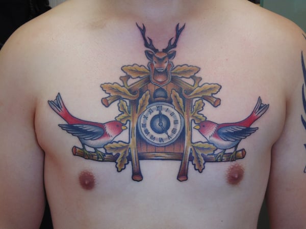 A colorful traditional cuckoo clock tattoo on the chest with birds and bold outlines — by Samuel Connelly, san diego, ca