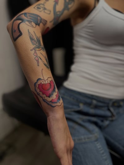 A colorful traditional sleeve tattoo featuring a bold heart design on the full sleeve — by Maddie Ramirez, los angeles