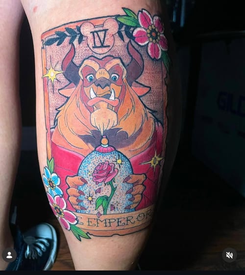 A colorful neo-traditional tattoo of the Beast from Beauty and the Beast, holding a rose in a glass dome, styled as a tarot card with floral accents on the thigh — by Jessica Linden, los angeles