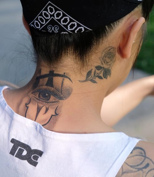 A bold black and grey tattoo featuring a realistic eye with scales and a rose on the neck — by Johnny Ayala, los angeles