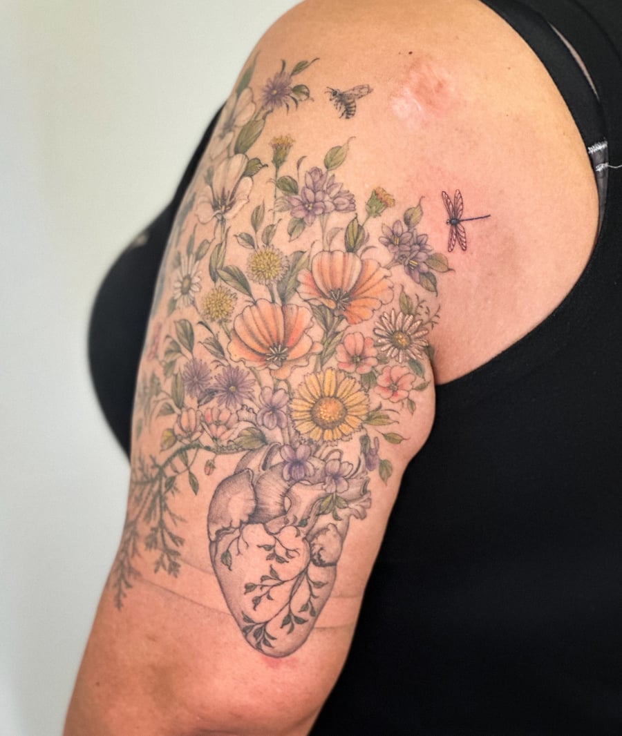 A colorful illustrative tattoo of a heart with flowers on the upper arm, featuring delicate floral details — by Melanie Benoit, los angeles