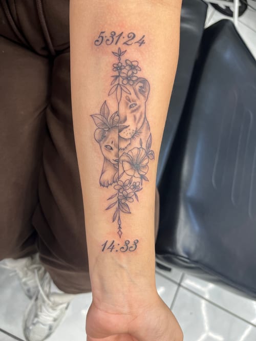 A fine line black and grey tattoo on the forearm featuring two lion cubs surrounded by flowers, with script numbers above and below — by Mr._Folks, los angeles