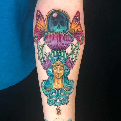 A colorful neo-traditional tattoo on the forearm depicting a woman's face with floral and skull elements in an ornate style — by Sandra Price, los angeles