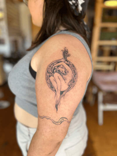 A black and grey linework tattoo of a woman curled up within a circular design on the upper arm, featuring intricate line details and a flowing pattern — by Dylan Aiello, los angeles