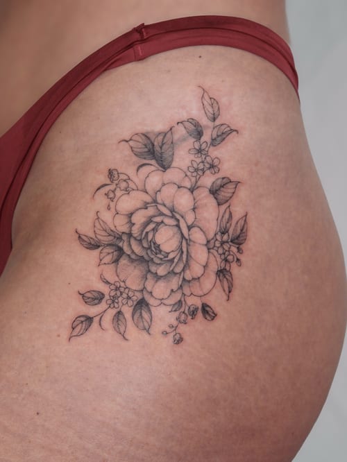 A delicate black and grey fine line flower bouquet tattoo on the hip — by Melanie Benoit, los angeles
