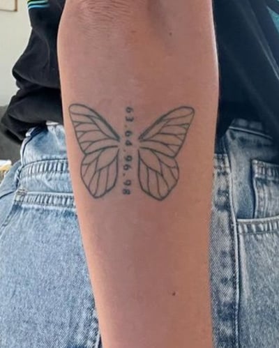 A minimalist black linework butterfly tattoo on the forearm with numbers along the body — by Melanie Benoit, los angeles