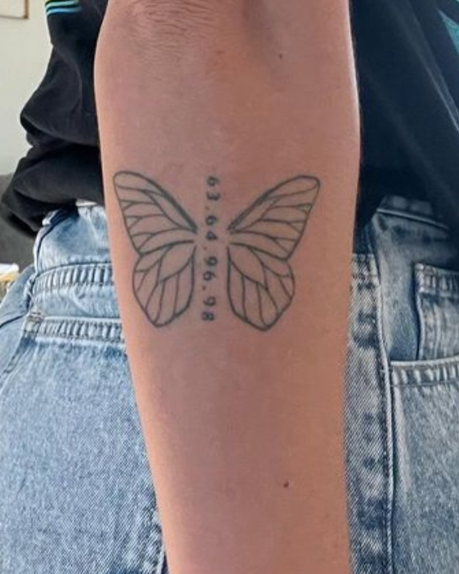 A minimalist black linework butterfly tattoo on the forearm with numbers along the body — by Melanie Benoit, los angeles