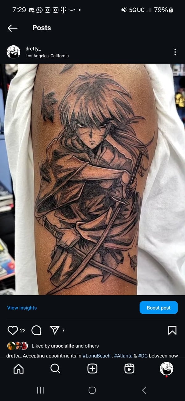 A black and grey anime-style tattoo on the upper arm depicting a character with a sword, featuring bold lines and dynamic shading — by Dretty, long beach, ca