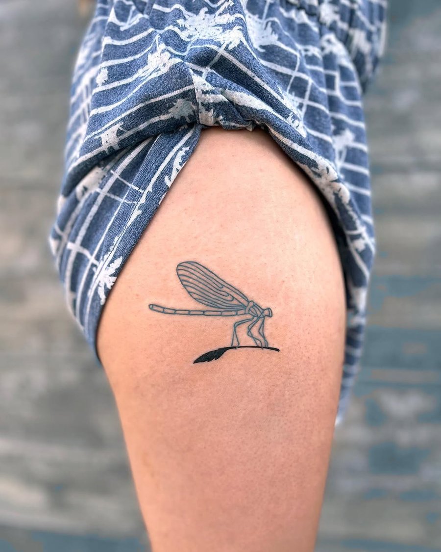 A minimalist linework dragonfly tattoo on the thigh, featuring delicate black and grey lines — by Dylan Aiello, los angeles