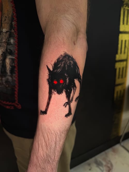 A dark blackwork tattoo of a creepy creature with red eyes on the forearm, featuring a graphic and eerie style — by Kiera Garvin, los angeles