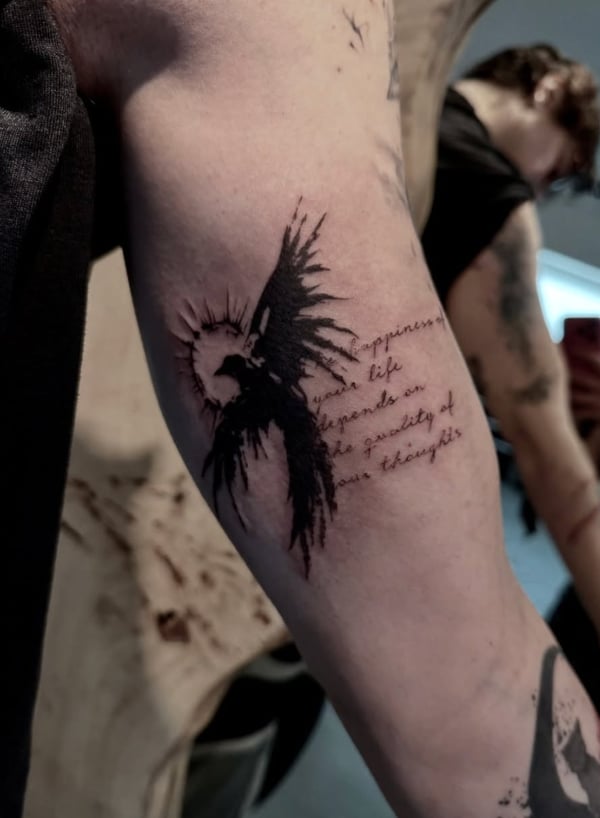 A black and grey tattoo on the inner arm featuring a stylized bird with spread wings and a quote in elegant lettering — by zitronxus, los angeles
