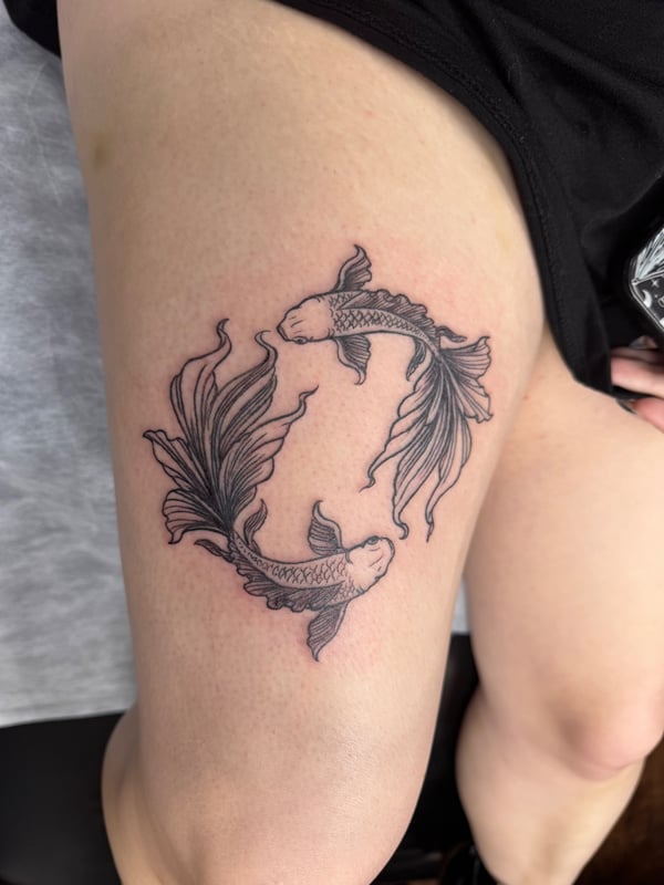 Two koi fish in a delicate blackwork style on the thigh, featuring fine line details and minimal shading — by Sandra Price, ventura, ca