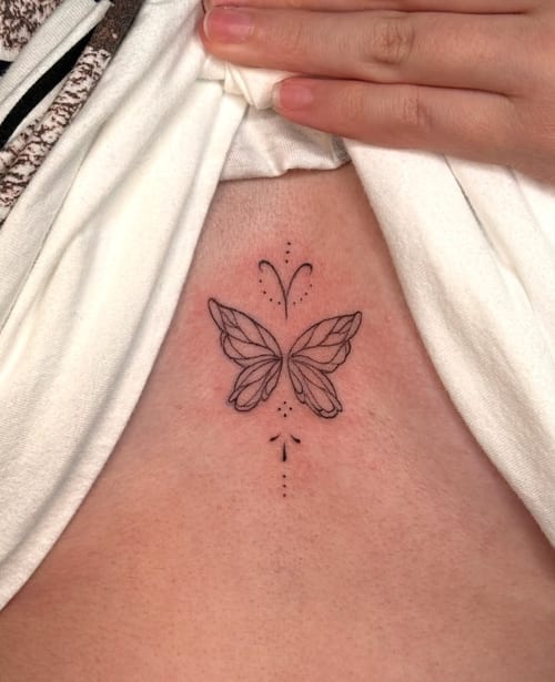 A minimalist fine line butterfly tattoo on the sternum with delicate dotwork accents in black ink — by NJ TATTOOZ, los angeles
