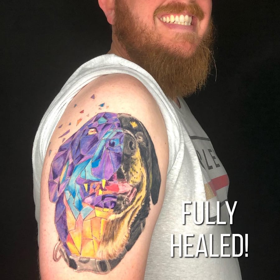 A colorful geometric and realistic dog portrait tattoo on the upper arm, featuring bold shapes and vibrant colors — by Sandra Price, los angeles