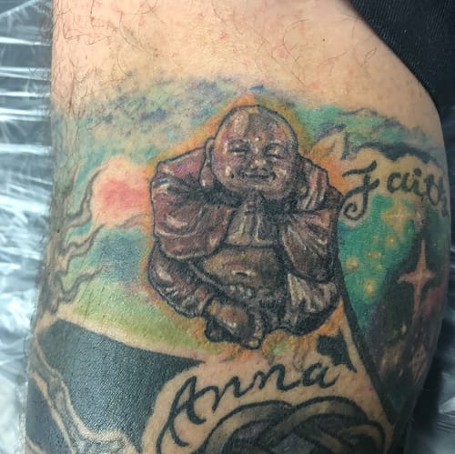 A colorful tattoo of a Buddha statue on the arm, featuring realistic details and spiritual themes — by Sandra Price, los angeles