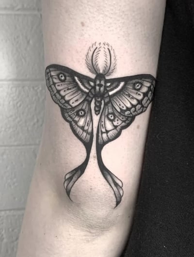 A black and grey linework tattoo of a moth on the arm, featuring intricate patterns and bold outlines — by Shelby Bianco, los angeles