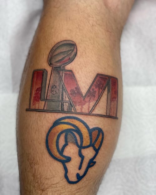 A colorful tattoo featuring the Super Bowl trophy and Rams logo on the leg, done in an illustrative style — by Sandra Price, los angeles