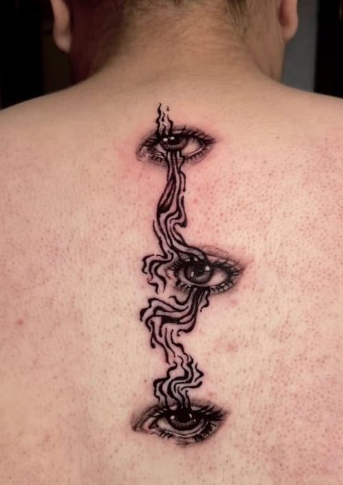A surreal blackwork tattoo on the back featuring three eyes connected by wavy lines, creating a flowing effect — by Shelby Bianco, los angeles