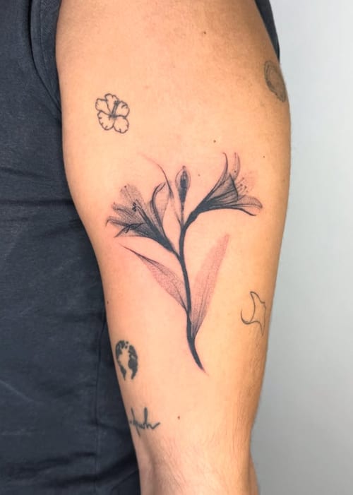 A minimalist fine line floral tattoo on the upper arm, featuring delicate black and grey flowers with subtle shading — by Level tattoo, los angeles