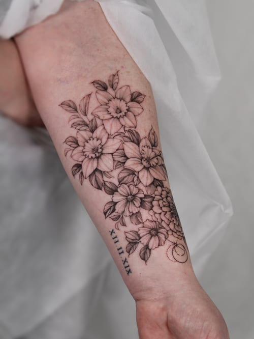 A delicate black and grey flower bouquet tattoo on the forearm with intricate shading and detail — by Melanie Benoit, los angeles