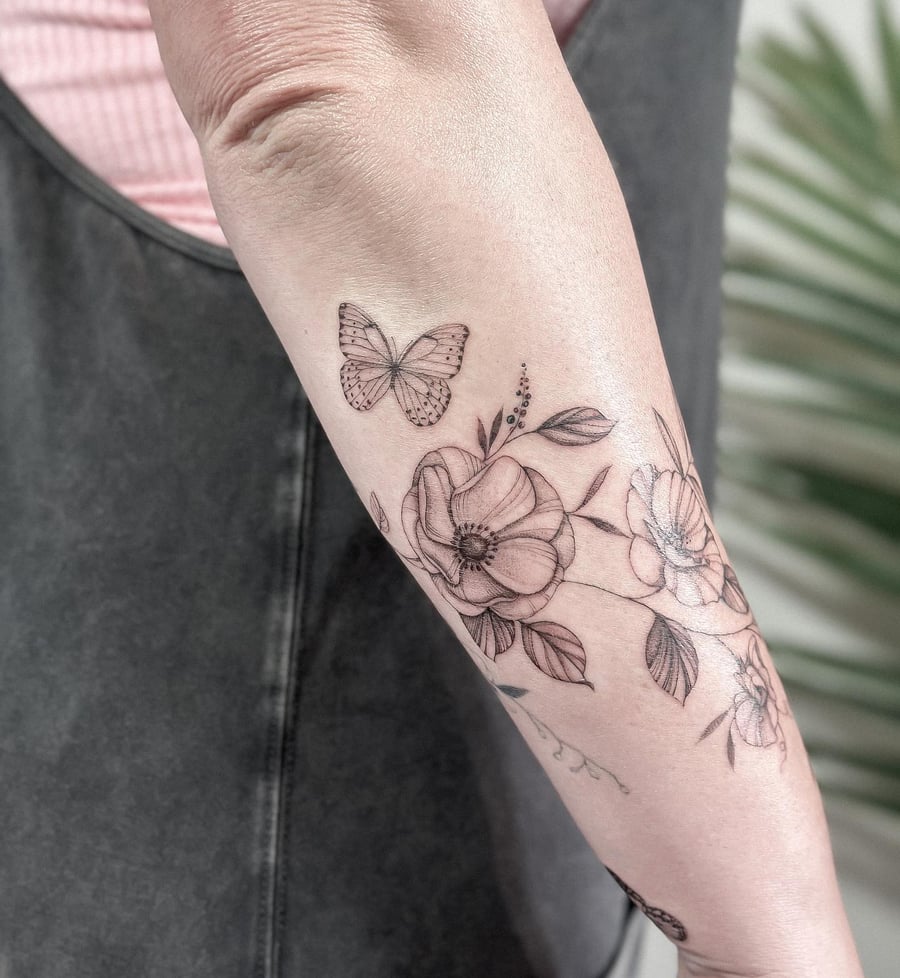 A delicate black and grey butterfly and floral tattoo on the forearm, featuring fine line work and minimalistic design — by Melanie Benoit, los angeles