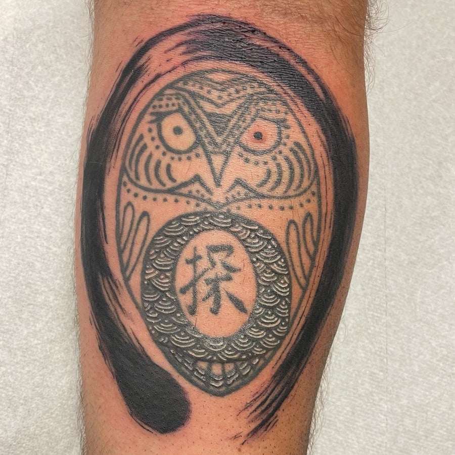 A bold blackwork owl tattoo on the leg featuring ornamental patterns and kanji script — by Sandra Price, los angeles