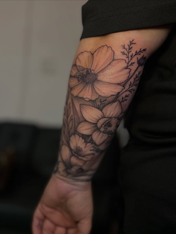 A delicate black and grey floral sleeve tattoo on the forearm — by Maddie Ramirez, palm desert, ca