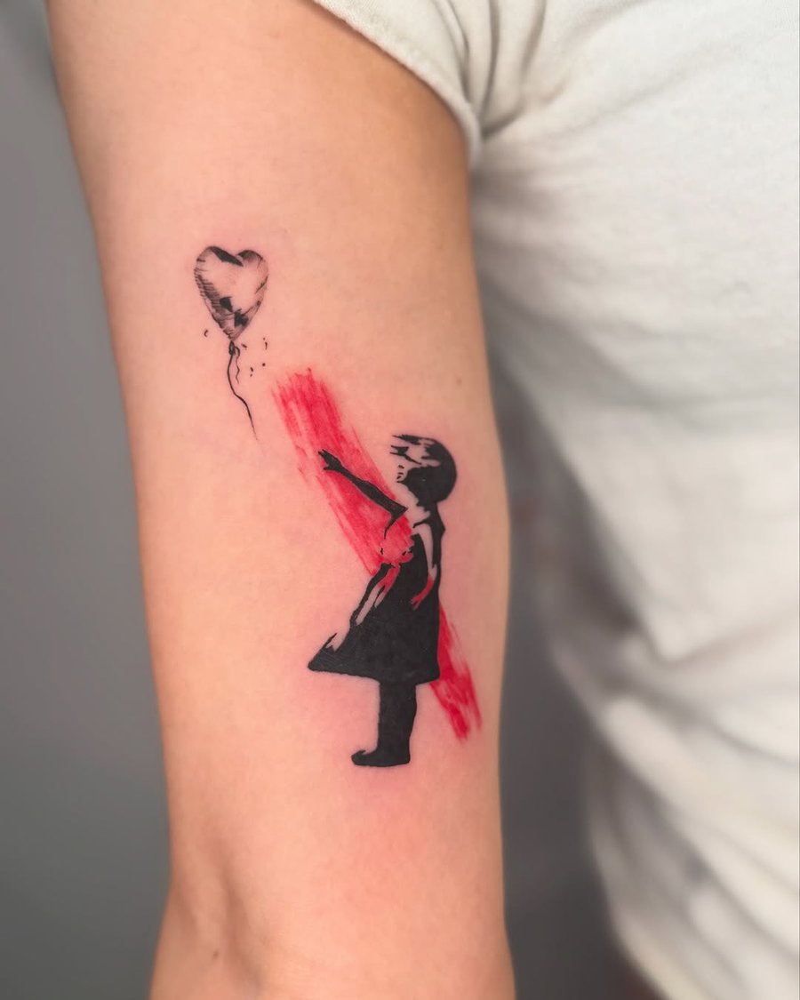 A bold stencil-style tattoo of a girl reaching for a heart-shaped balloon on the arm, featuring black and red ink — by zealous, los angeles