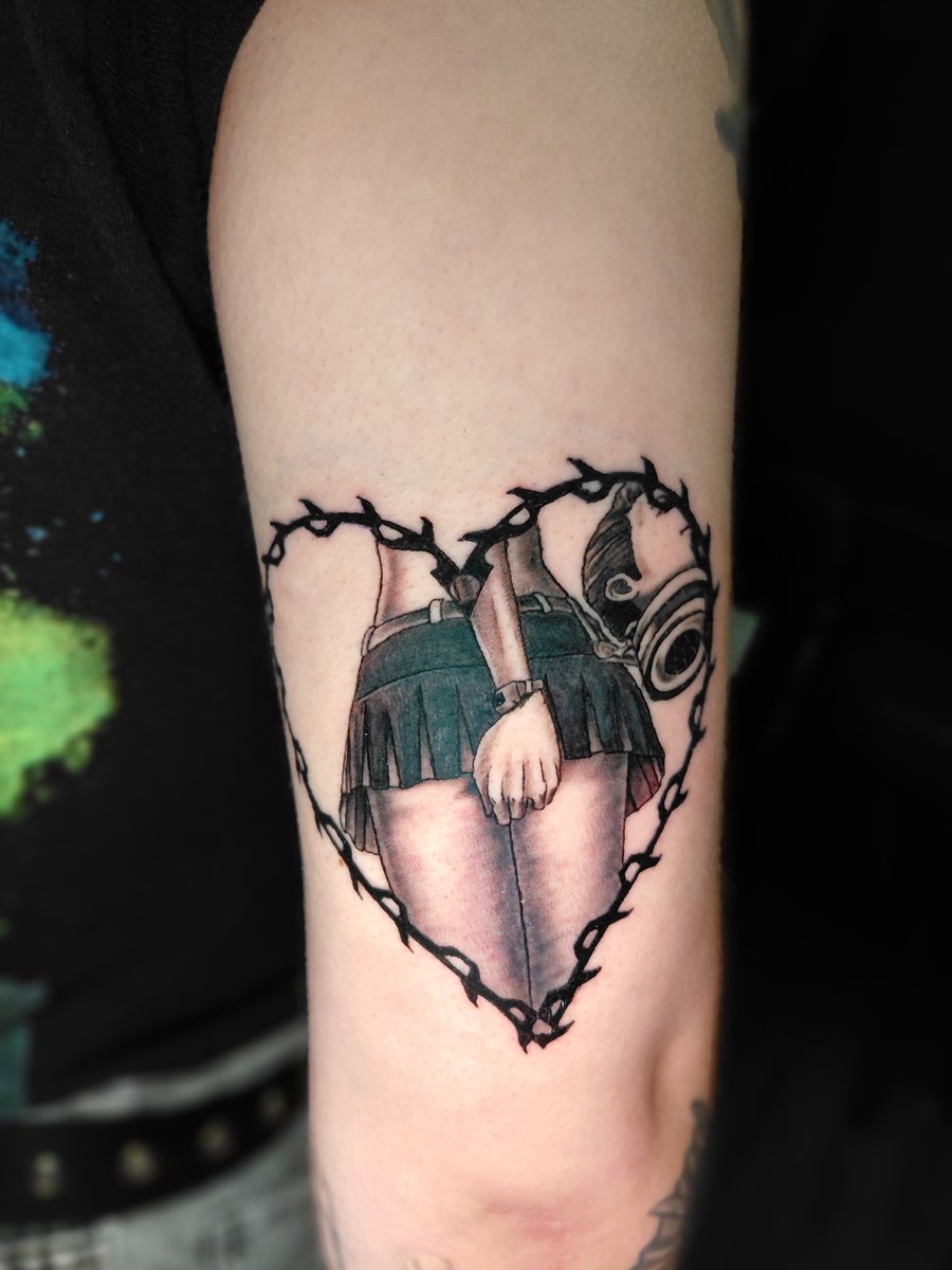 A graphic tattoo of a girl in a skirt holding a camera, framed by a heart on the arm — by anoetic.designs.ultd, los angeles