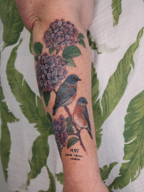 A colorful tattoo of birds perched on hydrangeas on the forearm, featuring realistic details and vibrant colors — by Melanie Benoit, los angeles