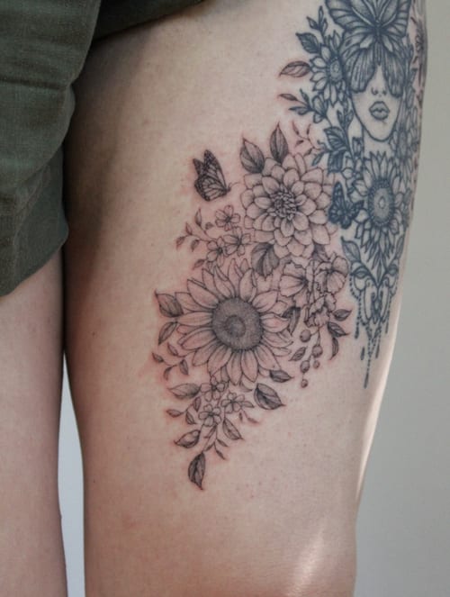 A delicate black and grey floral arrangement with a butterfly on the thigh, featuring intricate flower details — by Melanie Benoit, los angeles