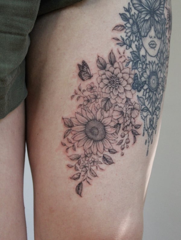 A delicate black and grey floral arrangement with a butterfly on the thigh, featuring intricate flower details — by Melanie Benoit, los angeles