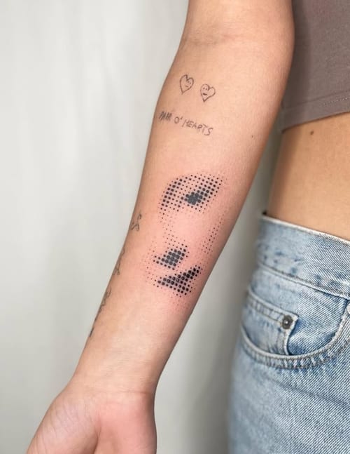 A minimalist dotwork tattoo of a face on the forearm, using black ink with a subtle and abstract design — by Level tattoo, los angeles