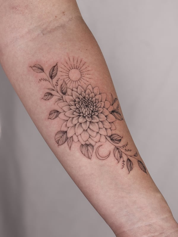 A delicate black and grey fine line tattoo of a flower with sun and moon elements on the forearm — by Melanie Benoit, los angeles