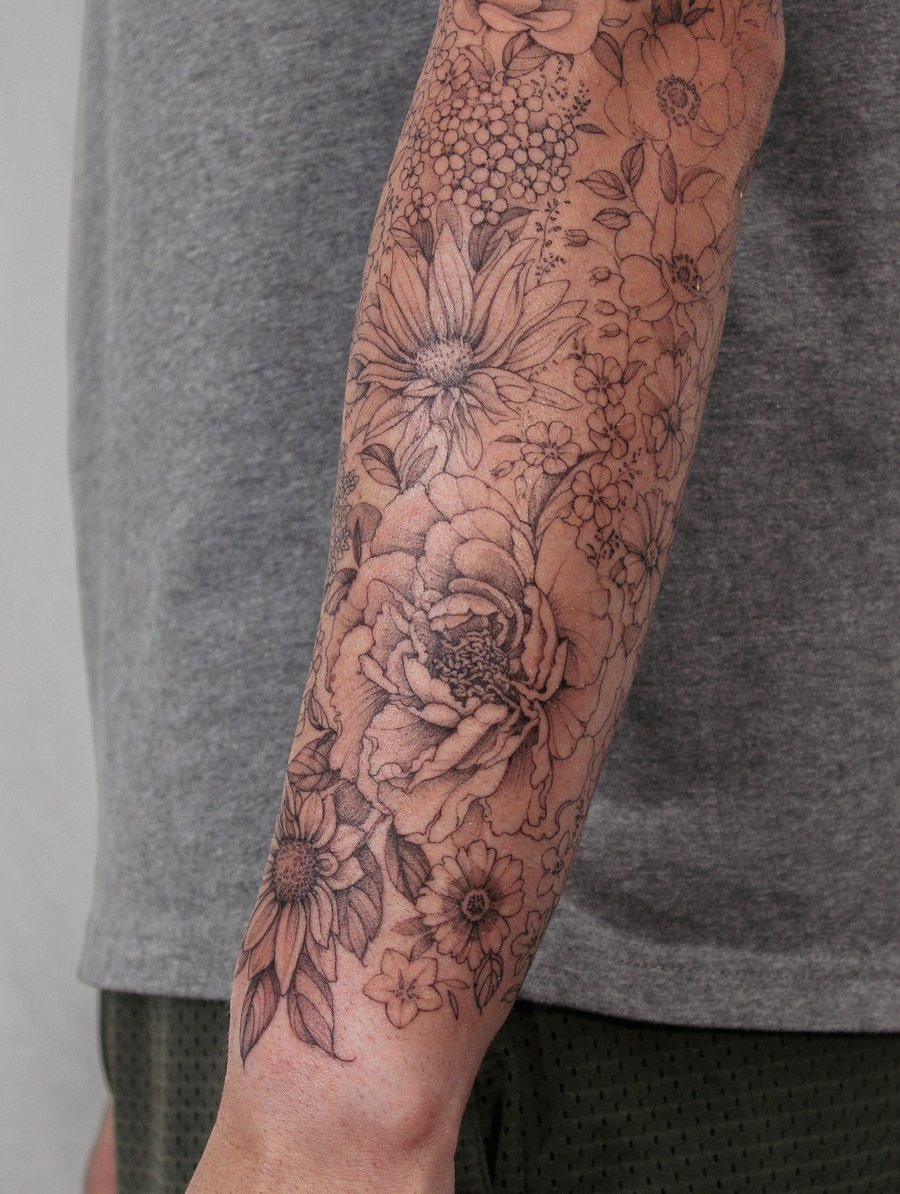 A delicate black and grey floral arrangement tattoo on the forearm featuring various flowers in an ornate design — by Melanie Benoit, los angeles