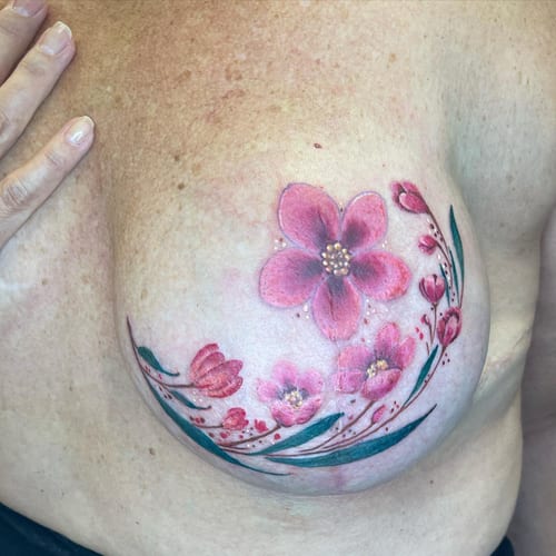 A delicate watercolor tattoo of pink flowers on the chest, featuring a romantic and soft design — by Sandra Price, los angeles