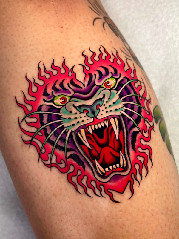A colorful Neo-Traditional tattoo of a roaring tiger's head with vibrant flames on the arm, featuring bold lines and vivid colors — by Megan Rose, long beach, ca