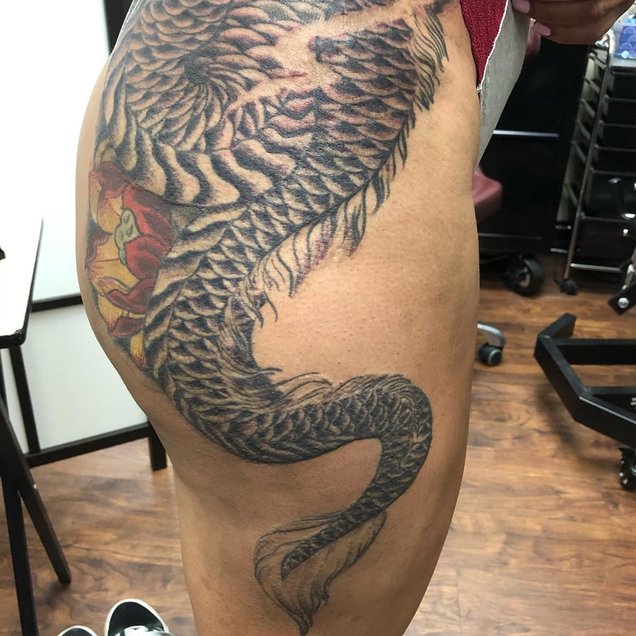 A bold Japanese dragon tattoo on the thigh with a mix of black and grey shading and some color accents — by Sandra Price, los angeles