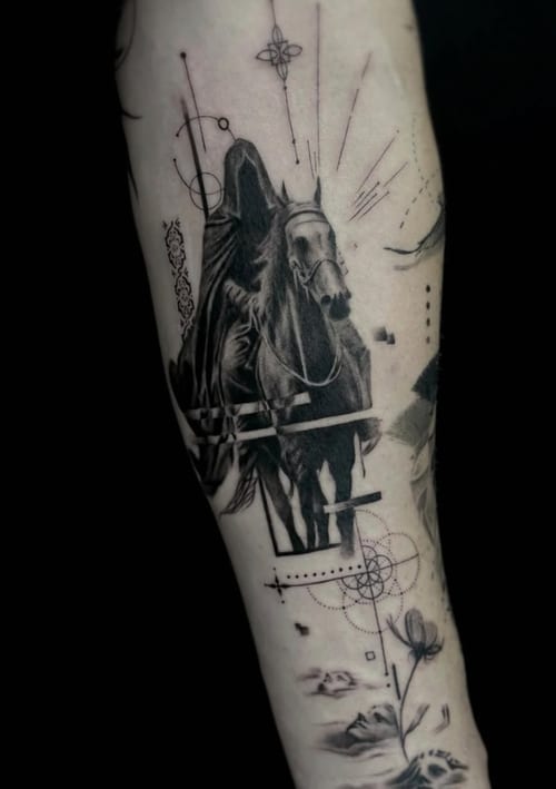 A black and grey surrealistic tattoo on the forearm featuring a hooded figure riding a horse, surrounded by abstract elements and faces — by Jian Liang, los angeles