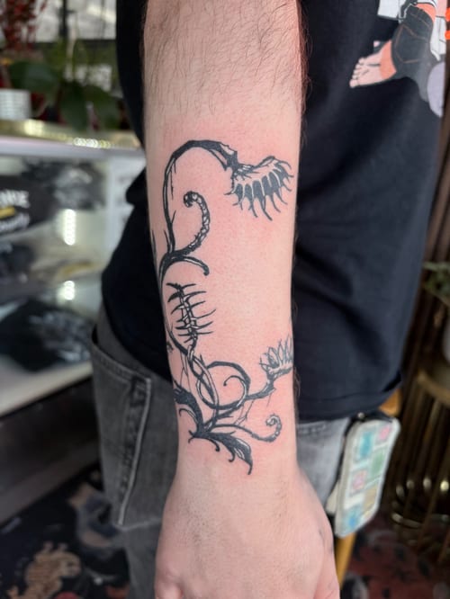 A black and grey linework tattoo of abstract floral designs on the forearm, featuring intricate vine-like patterns — by Hannah , los angeles