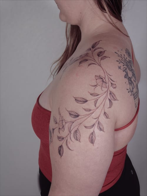 A delicate black and grey floral vine tattoo on the shoulder with fine line detailing — by Melanie Benoit, los angeles