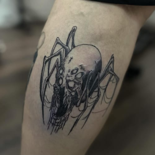 A dark blackwork tattoo of a spider with a skull on the leg, featuring fine line details — by Maddie Ramirez, los angeles