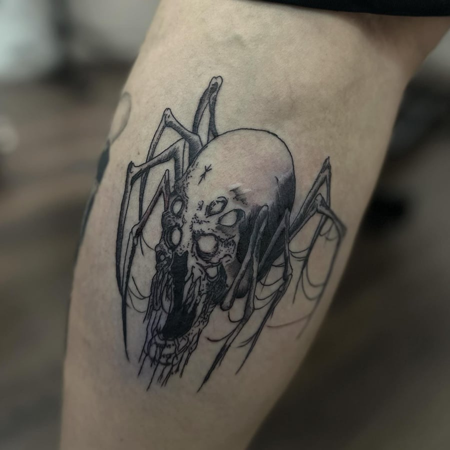 A dark blackwork tattoo of a spider with a skull on the leg, featuring fine line details — by Maddie Ramirez, los angeles